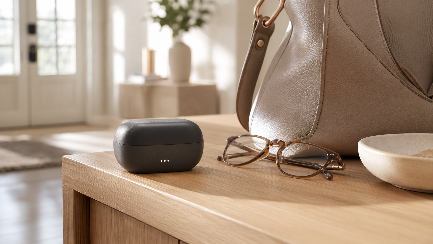 Portable hearing aid charging case beside glasses and a handbag